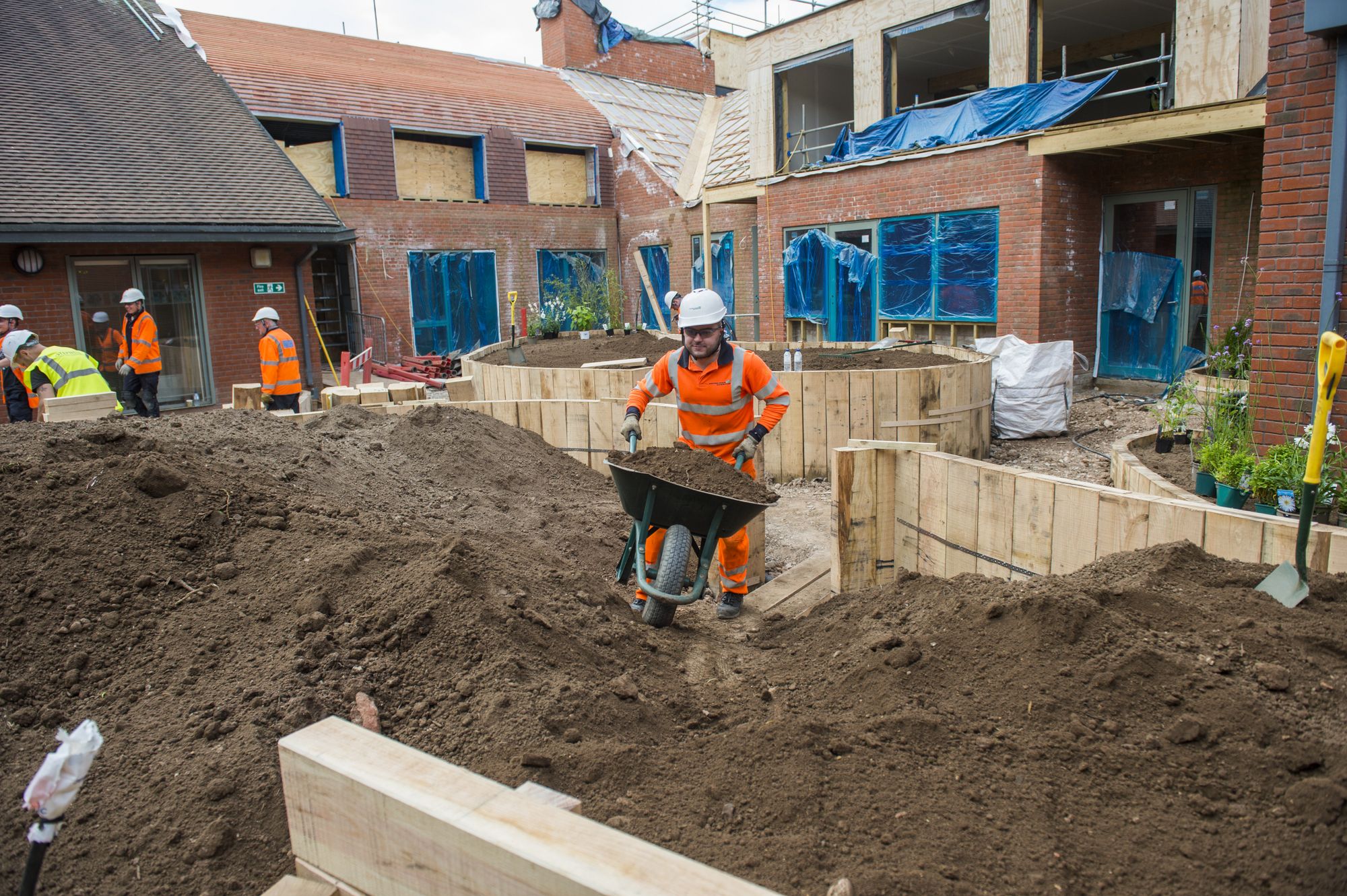 top soil being tipped into one of the two larger flower beds