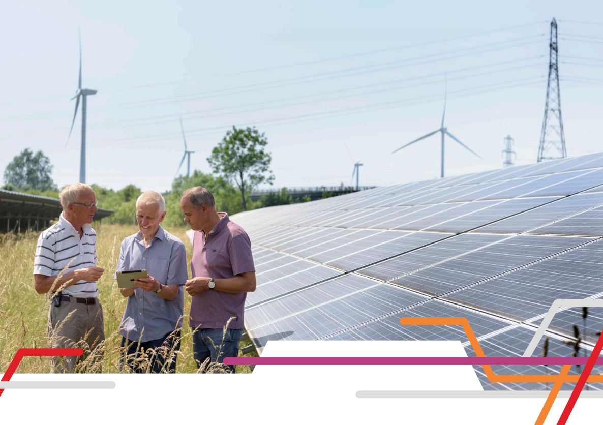 Community Energy group with smart device standing in front of a solar farm