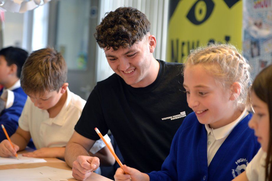 Worker and school children smiling with pencils in a workshop